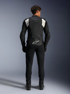 Alpinestars Dusk Airflow læderjakke, sort og hvid, set bagfra af en kører iført sorte bukser og støvler, med perforeret læder til ventilation, hvide accordion-strækpaneler på skuldrene og hvidt logo på den nederste del af ryggen