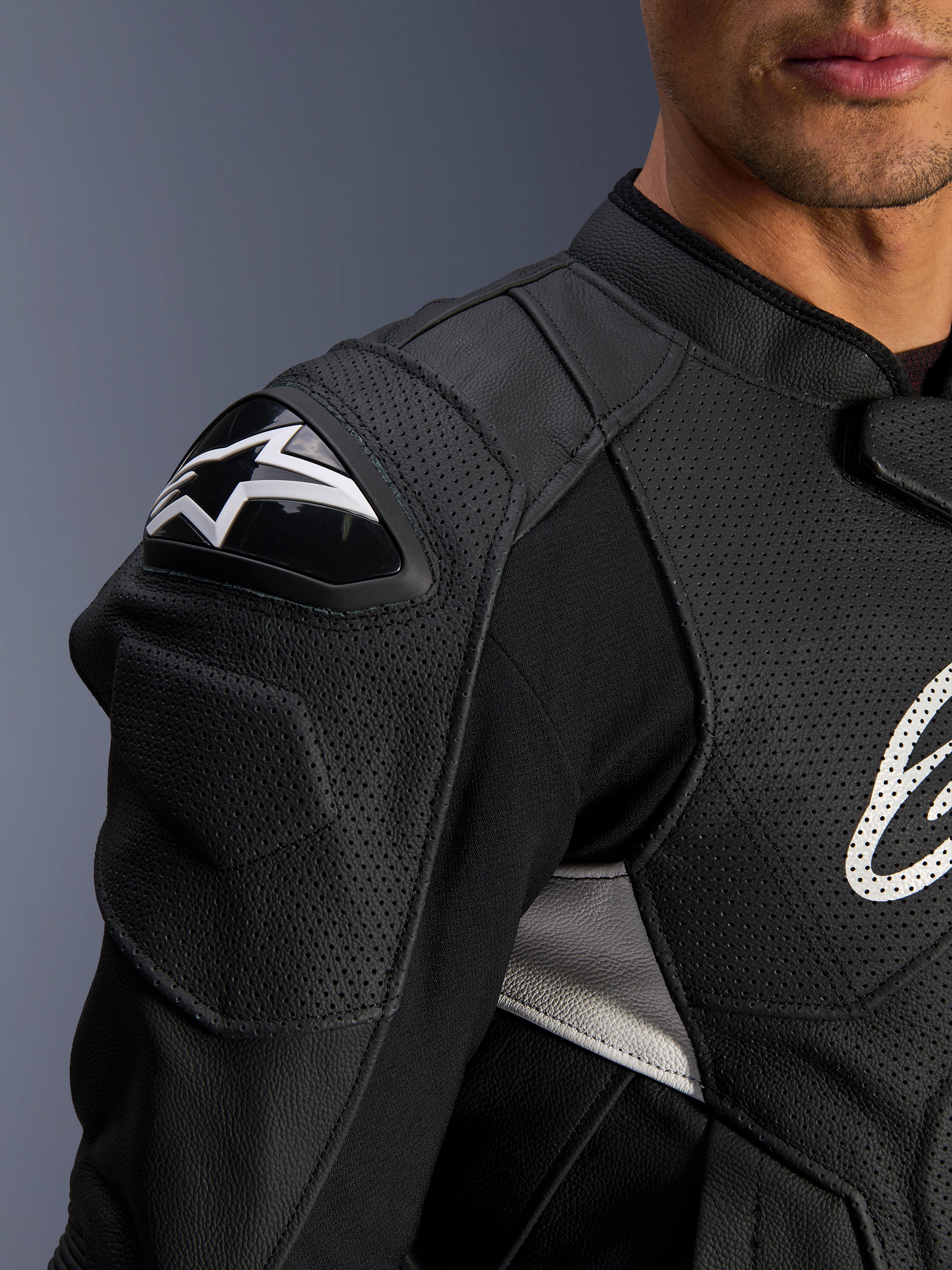 Alpinestars Dusk Airflow læderjakke, sort og hvid, nærbillede af skulder og bryst, perforeret læder til ventilation, DFS-skulderbeskyttelse med hvidt Alpinestars-logo, sportsligt design