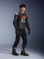 Mandlig kører iført Alpinestars GP Plus R V4 Airflow læderjakke, sort med rød fluo og hvide detaljer, perforeret læder og ASTARS brystlogo, sorte kørebukser og sorte motorcykelstøvler, sports performance-udstyr