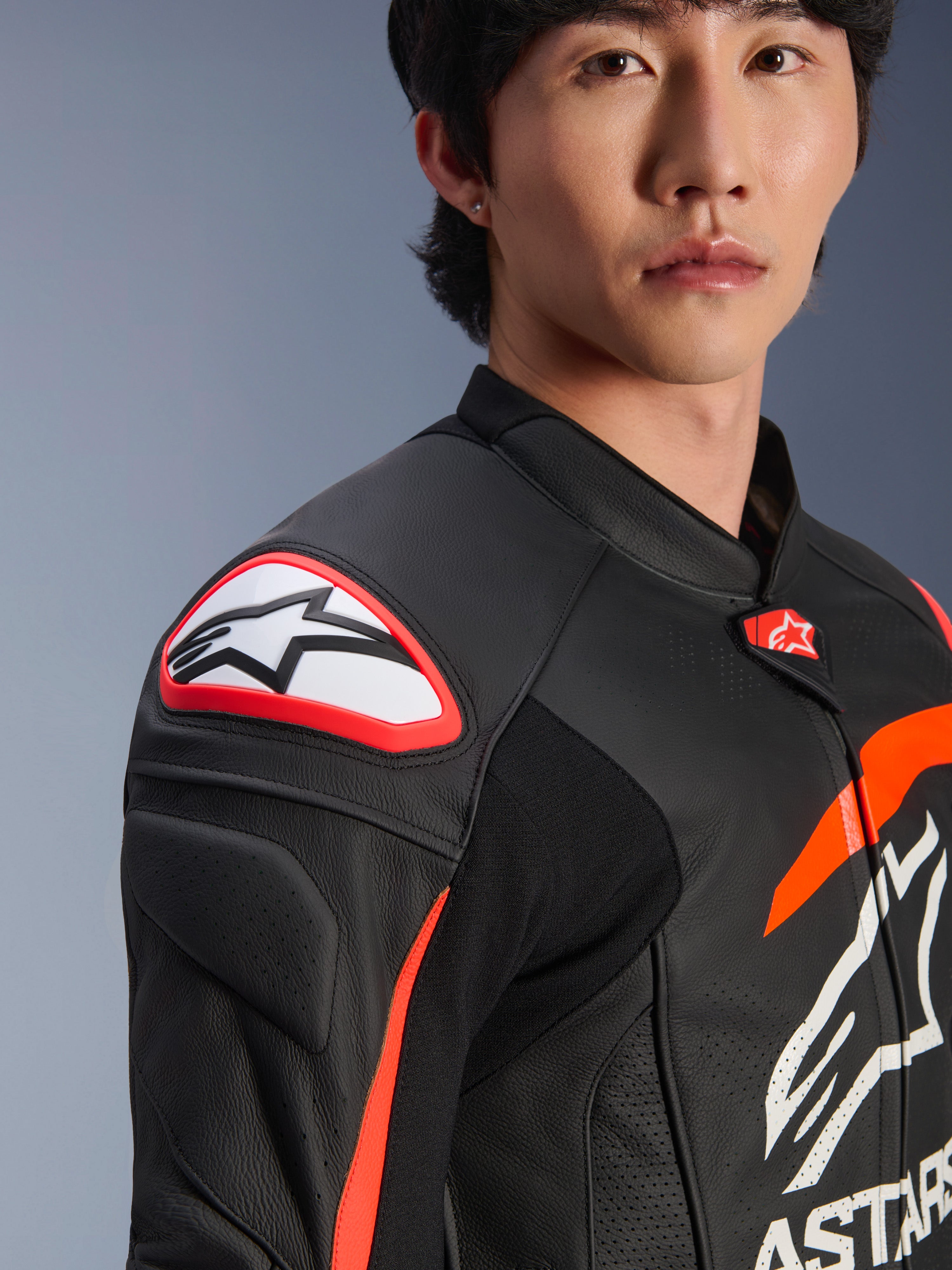 Alpinestars GP Plus R V4 Airflow læderjakke, sort, rød fluo og hvid, tæt på model iført jakken, med markant Astar-logo på skulderbeskytteren og perforeret læder på brystet for maksimal luftstrøm, professionelt motorsportstøj