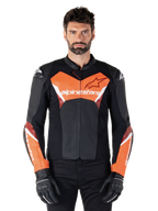 Alpinestars Faster V3 læderjakke, sportmotorcykeljakke, sort og rød fluo, båret af en mandlig model med sorte kørehandsker og bukser, med markant Alpinestars-branding på bryst og underarme, førsteklasses læderkonstruktion til kørsel på vej