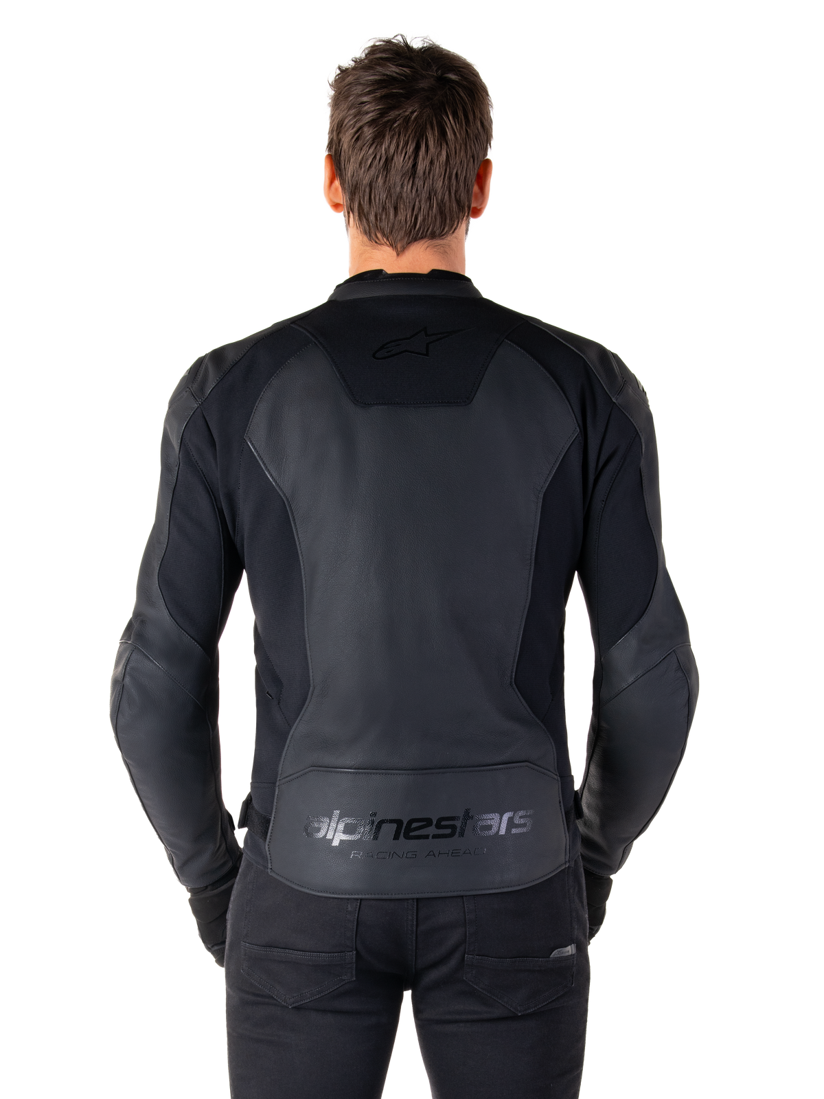 Set bagfra af en mand iført Alpinestars Faster V3 læderjakke i Black Black, med premium læderpaneler og fleksible strækindsatser, diskret 'alpinestars' og 'RACING AHEAD' branding på den nederste del af ryggen, atletisk sportspasform til motorcykelkørsel.