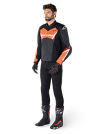 Alpinestars Faster V3 Airflow læderjakke, sort og rød fluo, båret af en mandlig model med sorte kørebukser, handsker og racingstøvler, med perforeret læder og en sportssilhuet.