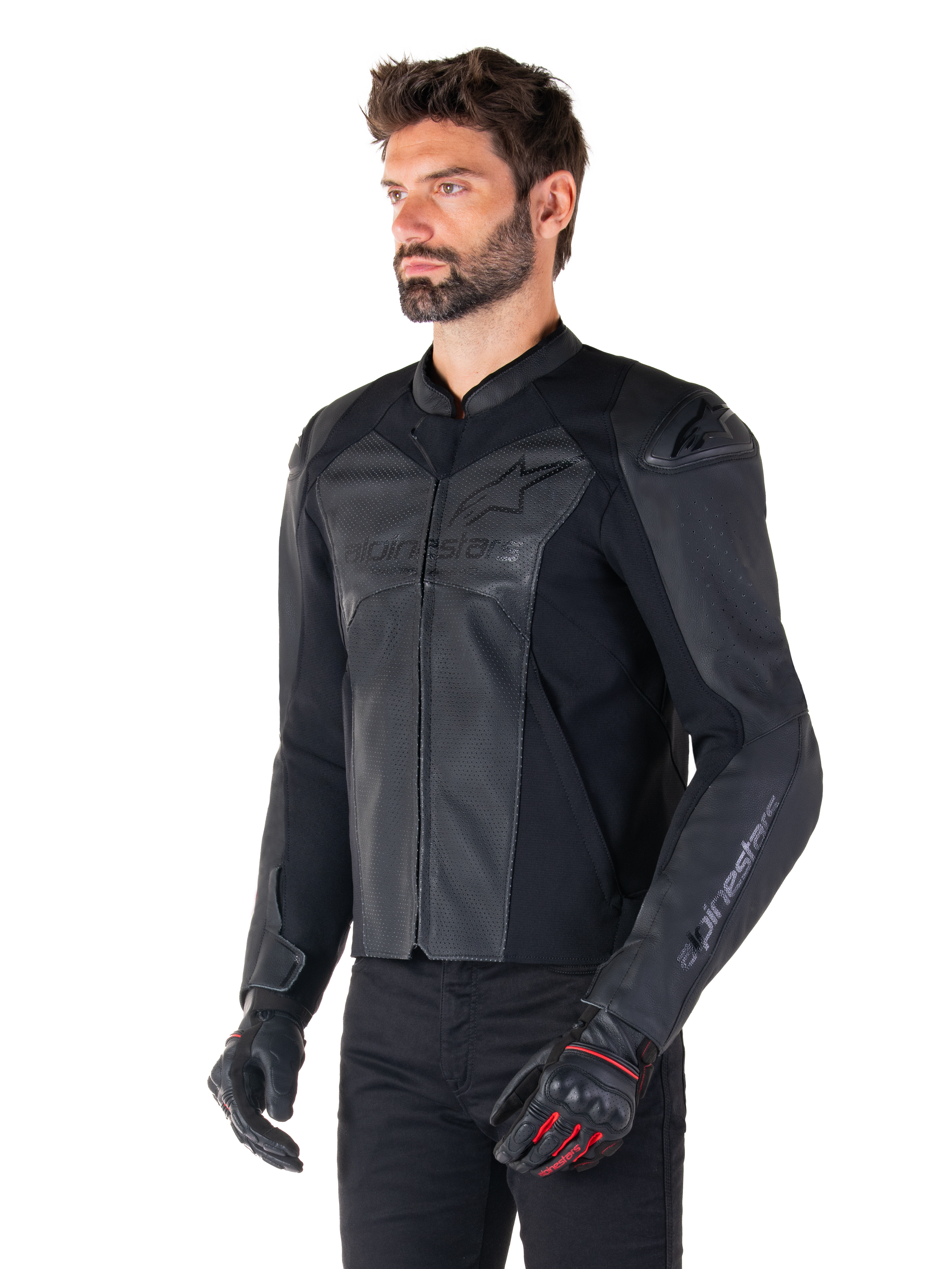 Model iført Alpinestars Faster V3 Airflow læderjakke i Black Black, sportskørejakke til motorcykel med perforeret læder og strækpaneler, kombineret med sorte bukser og sorte handsker med røde detaljer, strømlinet race-inspireret stil.