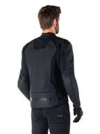 Alpinestars Faster V3 Airflow læderjakke, sort, set bagfra af en mand iført en sportsmotorcykeljakke i læder, med perforerede rygpaneler, strækpaneler og Alpinestars-branding på den nederste kant, kombineret med sorte bukser og handsker