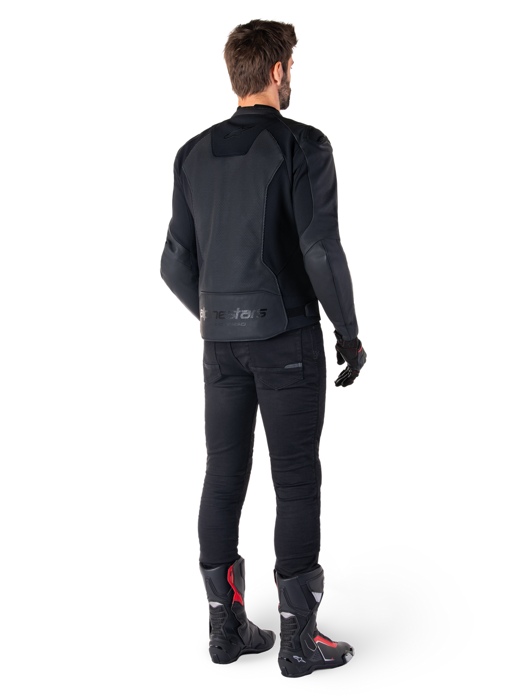 Alpinestars Faster V3 Airflow læderjakke, sort, set bagfra af en mand iført en sportslæderjakke med perforerede rygpaneler og Alpinestars-branding, stylet med sorte kørebukser og sort-røde støvler.
