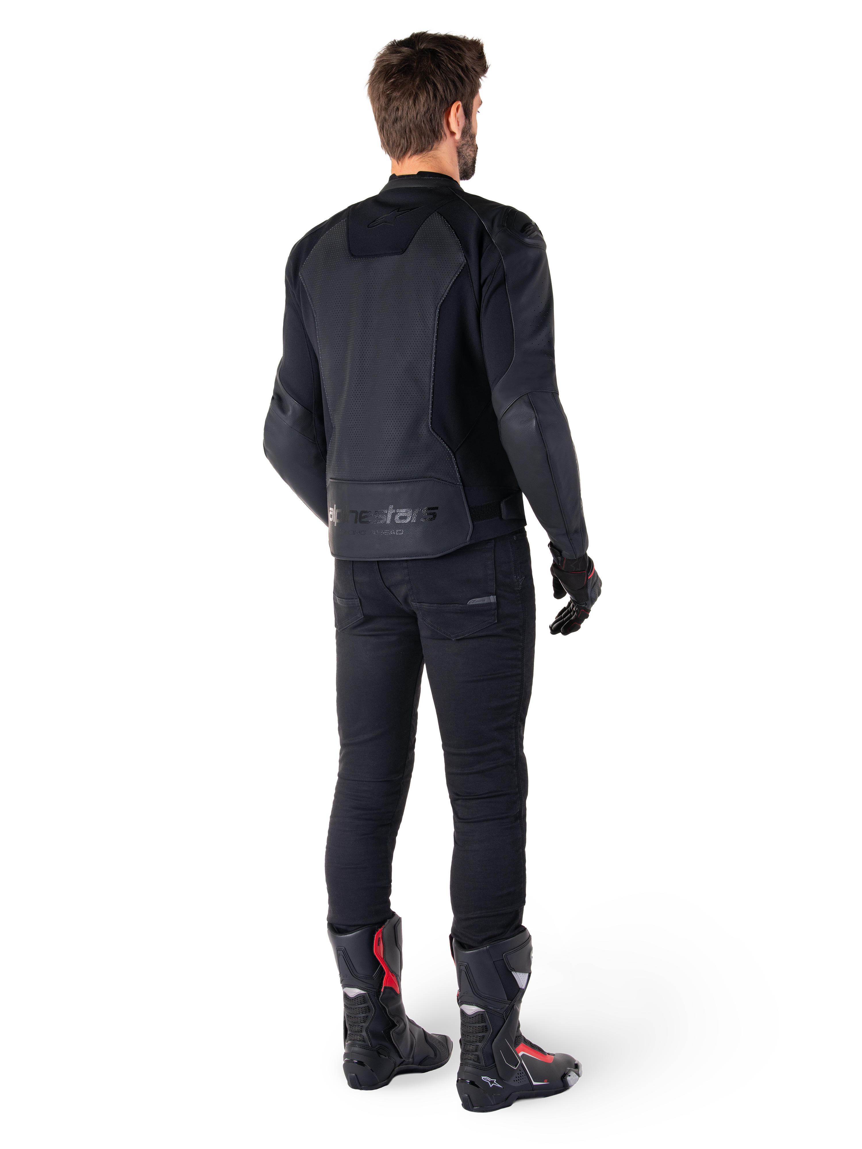 Alpinestars Faster V3 Airflow læderjakke, sort, set bagfra af en mand iført en sportslæderjakke med perforerede rygpaneler og Alpinestars-branding, stylet med sorte kørebukser og sort-røde støvler.
