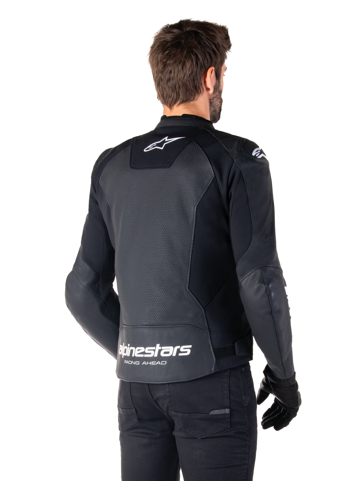 Alpinestars Faster V3 Airflow læderjakke, sort og hvid, set bagfra på en model, med perforeret læderryg for ventilation, hvide Astars-logoer på den øverste del af ryggen og nederst på lænden med 'Racing Ahead'-tekst, sporty design med strækpaneler til motorcykelbrug.