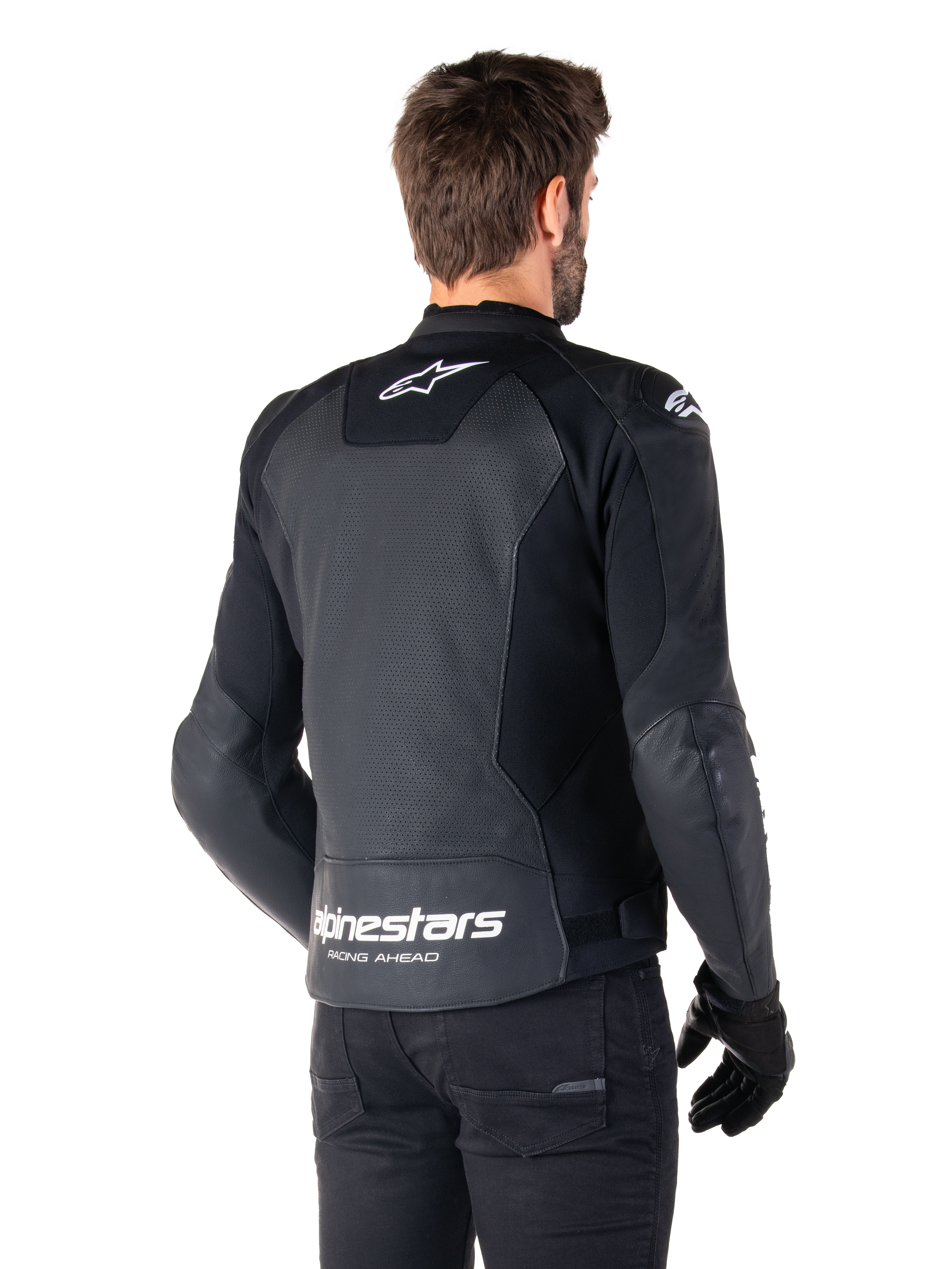 Alpinestars Faster V3 Airflow læderjakke, sort og hvid, set bagfra på en model, med perforeret læderryg for ventilation, hvide Astars-logoer på den øverste del af ryggen og nederst på lænden med 'Racing Ahead'-tekst, sporty design med strækpaneler til motorcykelbrug.