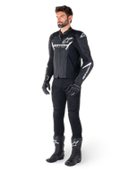 Model iført Alpinestars Faster V3 Airflow læderjakke, sort og hvid, med perforeret læder og hvide Alpinestars-logoer, kombineret med sorte kørebukser, handsker og støvler, sportsorienteret motorcykeludstyr