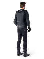 Alpinestars Faster V3 Airflow læderjakke, sort og hvid, set bagfra med perforerede læderpaneler og tydelig Alpinestars-branding på lænden, båret af en kører med sorte kørebukser, handsker og støvler.