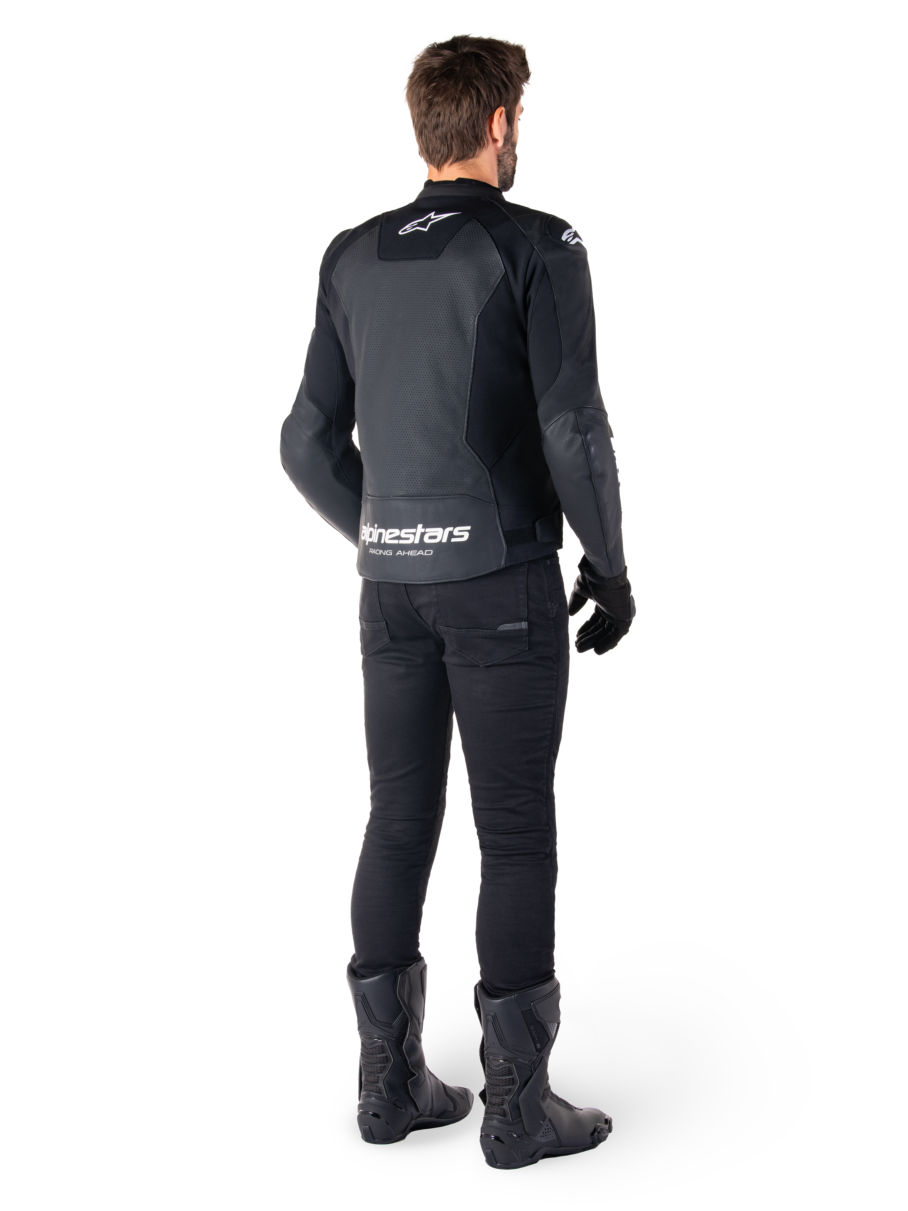 Alpinestars Faster V3 Airflow læderjakke, sort og hvid, set bagfra med perforerede læderpaneler og tydelig Alpinestars-branding på lænden, båret af en kører med sorte kørebukser, handsker og støvler.