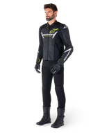 Mandlig rytter iført Alpinestars Faster V3 Airflow læderjakke i sort, hvid og gul fluo, kombineret med sorte motorcykelbukser og støvler, med perforerede læderpaneler, hvide logodetaljer og neongule accenter, professionelt sportsudstyr til kørsel