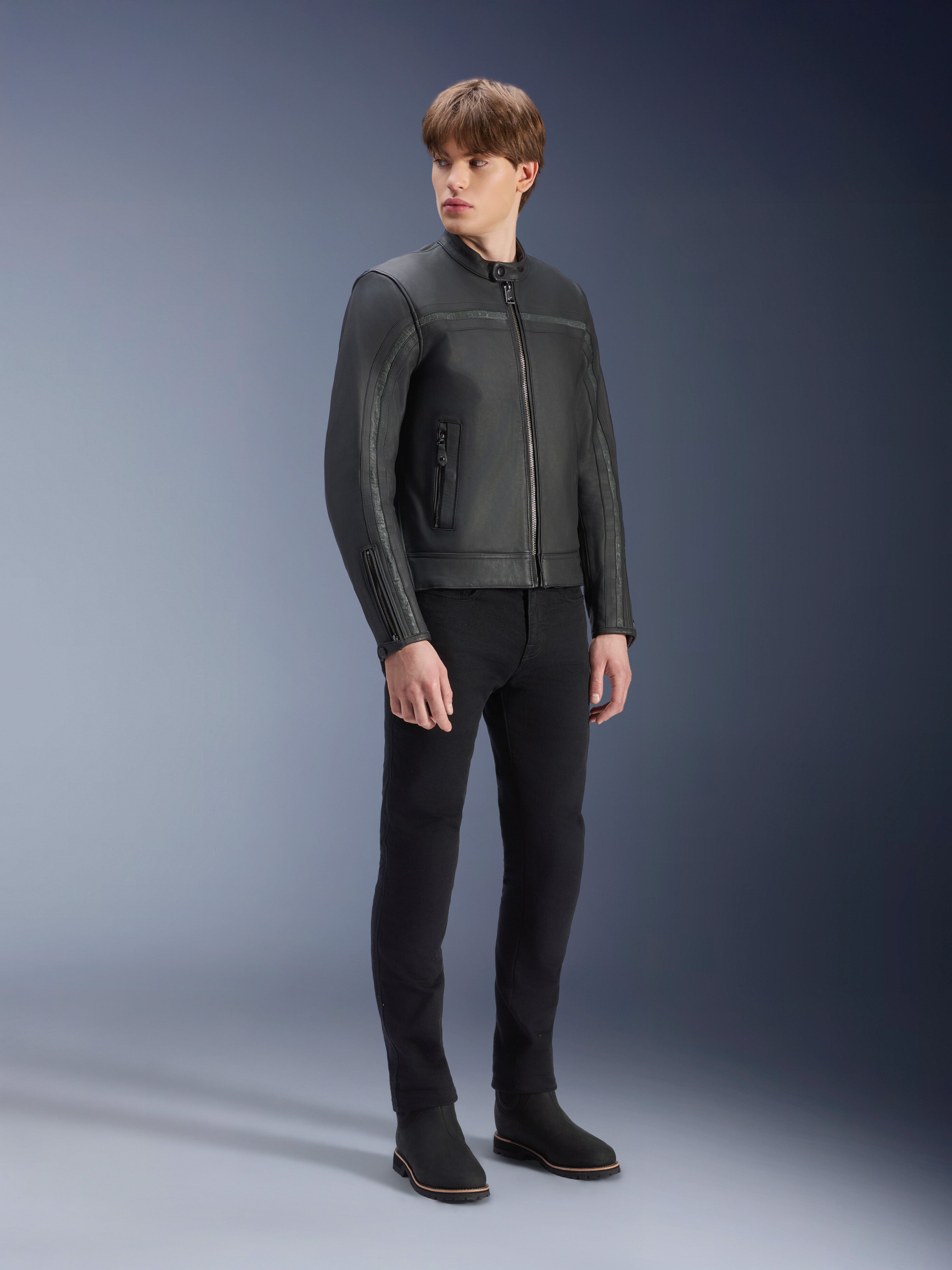 Alpinestars Dyno Leather Jacket in Black, premium bovine leather motorcycle jacket, worn by male model with black slim-fit pants and black boots, heritage-inspired minimalist design for urban contemporary riding, studio setting.