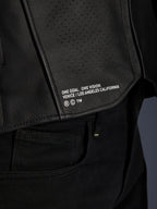 Nærbillede af Alpinestars Atem V5 læderjakken i sort, der viser det nederste rygpanel med 'ONE GOAL. ONE VISION. VENICE / LOS ANGELES CALIFORNIA' branding og perforeret lædertekstur.