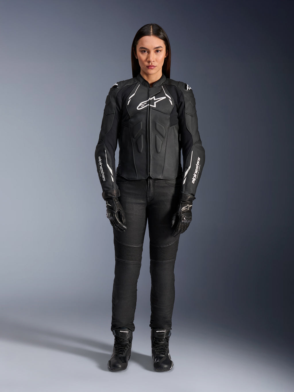Alpinestars Stella Dusk læderjakke til kvinder, sort og hvid, båret af en model med matchende sorte bukser og støvler, set forfra, med hvide Alpinestars-logoer på brystet og ærmerne, beskyttelsesudstyr i premium okselæder til kvinder