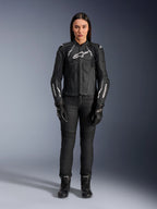 Alpinestars Stella Dusk læderjakke til kvinder, sort og hvid, båret af en model med matchende sorte bukser og støvler, set forfra, med hvide Alpinestars-logoer på brystet og ærmerne, beskyttelsesudstyr i premium okselæder til kvinder