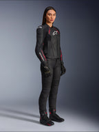 Alpinestars Stella Dusk læderjakke til damer, sort, Diva Pink og hvid, båret af en kvindelig model med sorte motorcykelbukser og støvler, strømlinet læderkonstruktion med lyserøde detaljer og hvidt logo