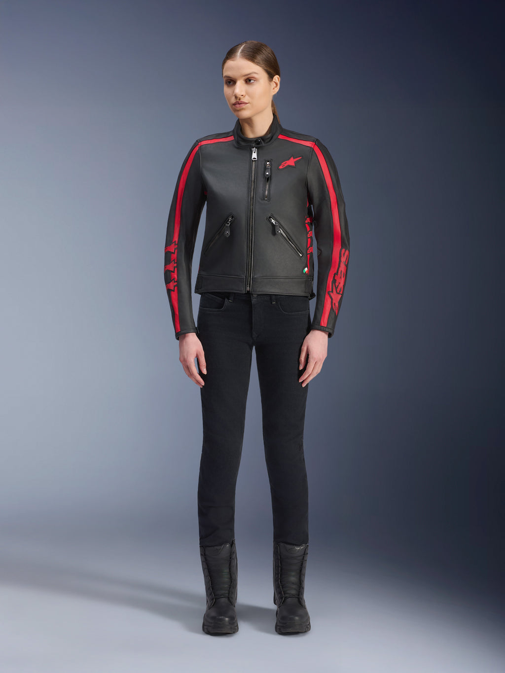 Alpinestars Stella Dyno læderjakke, motorcykeljakke til damer, sort og Haute Red, med røde racerstriber på skuldre og ærmer, rødt stjernelogo på brystet, båret med sorte slim-fit bukser og støvler, premium bovinelæder med et moderne heritage-design