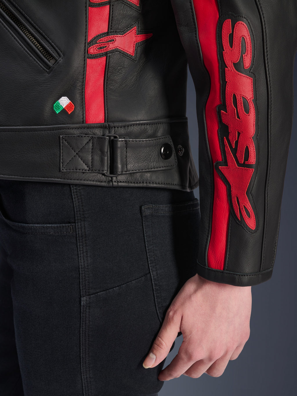 Alpinestars Stella Dyno læderjakke, motorcykeljakke i læder til damer, Sort Haute Red, nærbillede af talje og ærme, røde racerstriber med Alpinestars-branding, justerbar taljerem, lille broderet italiensk flag, førsteklasses konstruktion i bovinelæder