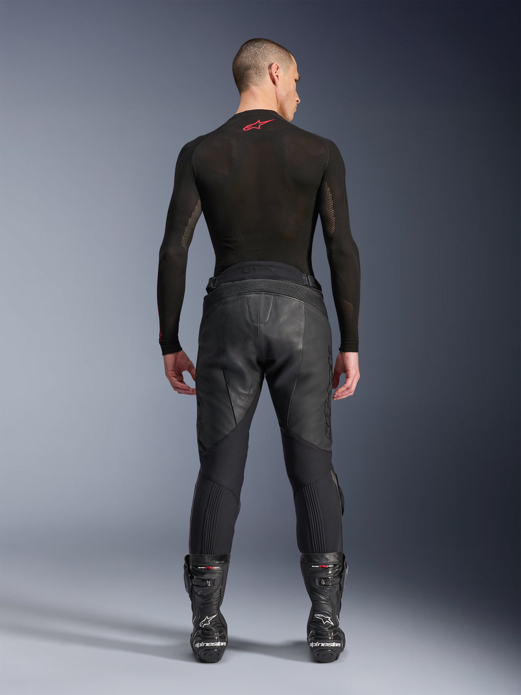 Alpinestars Missile V3 læderbukser, sort, set bagfra på model iført sort langærmet kompressionsbluse og racingstøvler, premium læderkonstruktion med høj talje-overlap og strækzoner, professionelt motorcykelracerudstyr