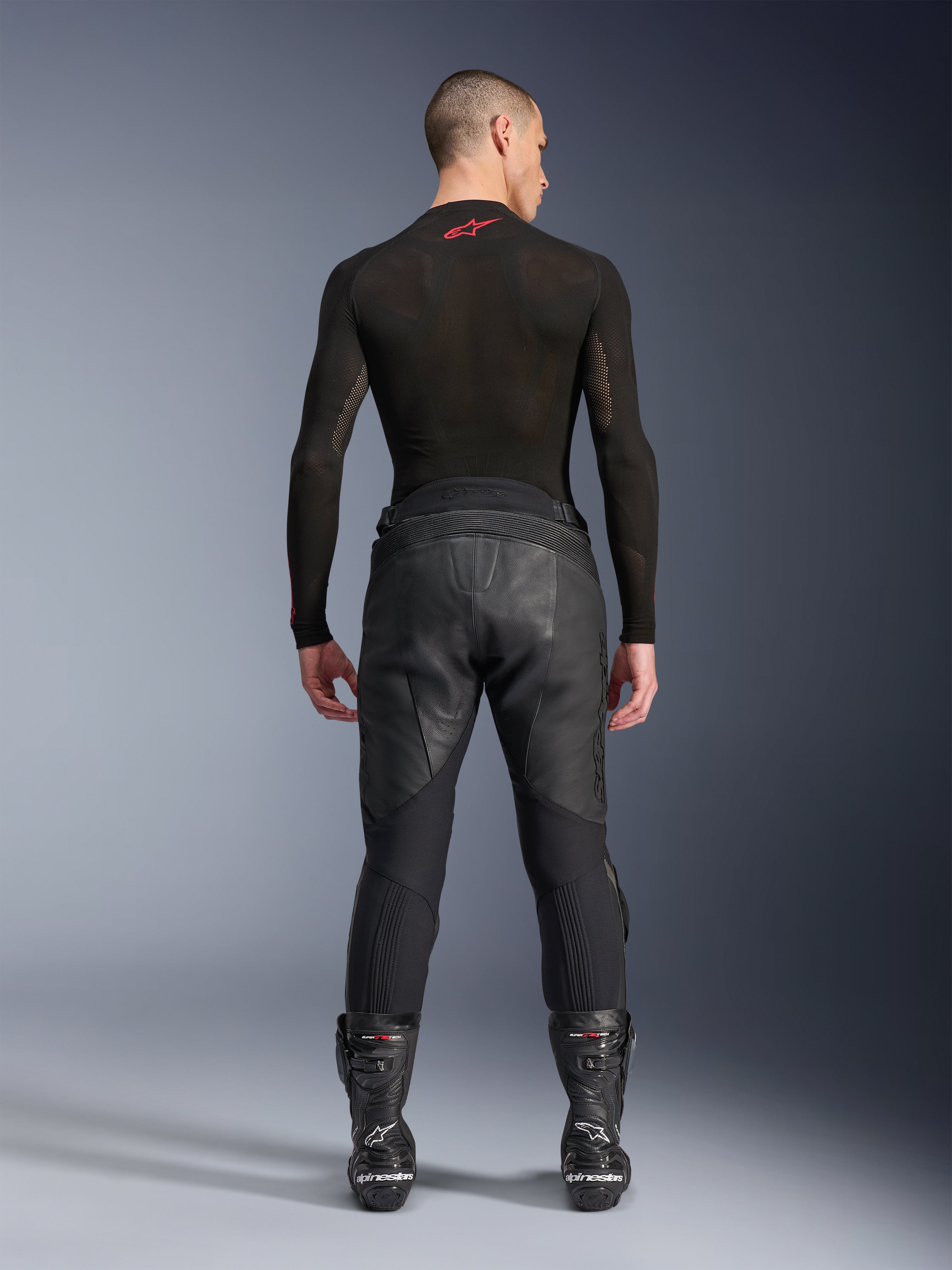 Alpinestars Missile V3 læderbukser, sort, set bagfra på model iført sort langærmet kompressionsbluse og racingstøvler, premium læderkonstruktion med høj talje-overlap og strækzoner, professionelt motorcykelracerudstyr