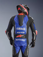 Alpinestars Yamaha GP-R7 ét-delt læderdragt, set bagfra, metallic blå og sort med hvide og røde detaljer, fremtrædende Yamaha- og GYTR-branding, aerodynamisk fartpukkel, båret med en matchende racinghjelm og handsker for et professionelt, baneklar look