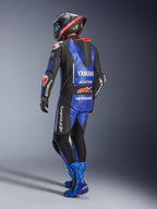 Alpinestars Yamaha GP-R7 læderdragt, metallisk blå, sort og hvid, set bagfra med aerodynamisk race-pukkel og Yamaha-branding, båret med matchende blå racerstøvler og hjelm, professionel performance-læderdragt til banekørsel
