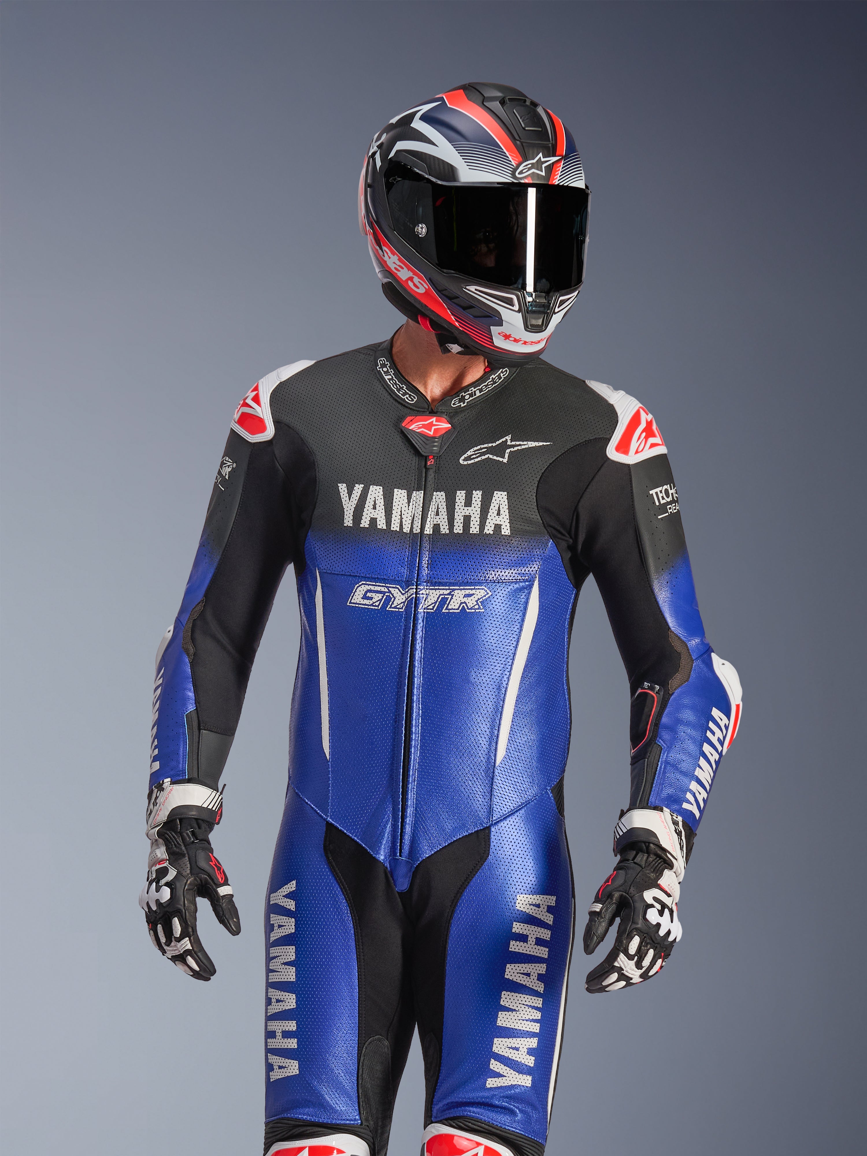 Yamaha GP-R7 1PC læderdragt, metallisk blå og sort med hvide og røde detaljer, båret med matchende hjelm og racerhandsker, med YAMAHA- og GYTR-branding, perforerede læderpaneler og Alpinestars-logoer, professionelt motorcykelracerudstyr