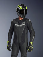 Alpinestars GP Force V2 læderdragt i én del, sort, båret af en kører med sort og neongul hjelm og handsker, med hvidt Alpinestars-branding på brystet, perforerede læderpaneler for ventilation og et professionelt racerklart design