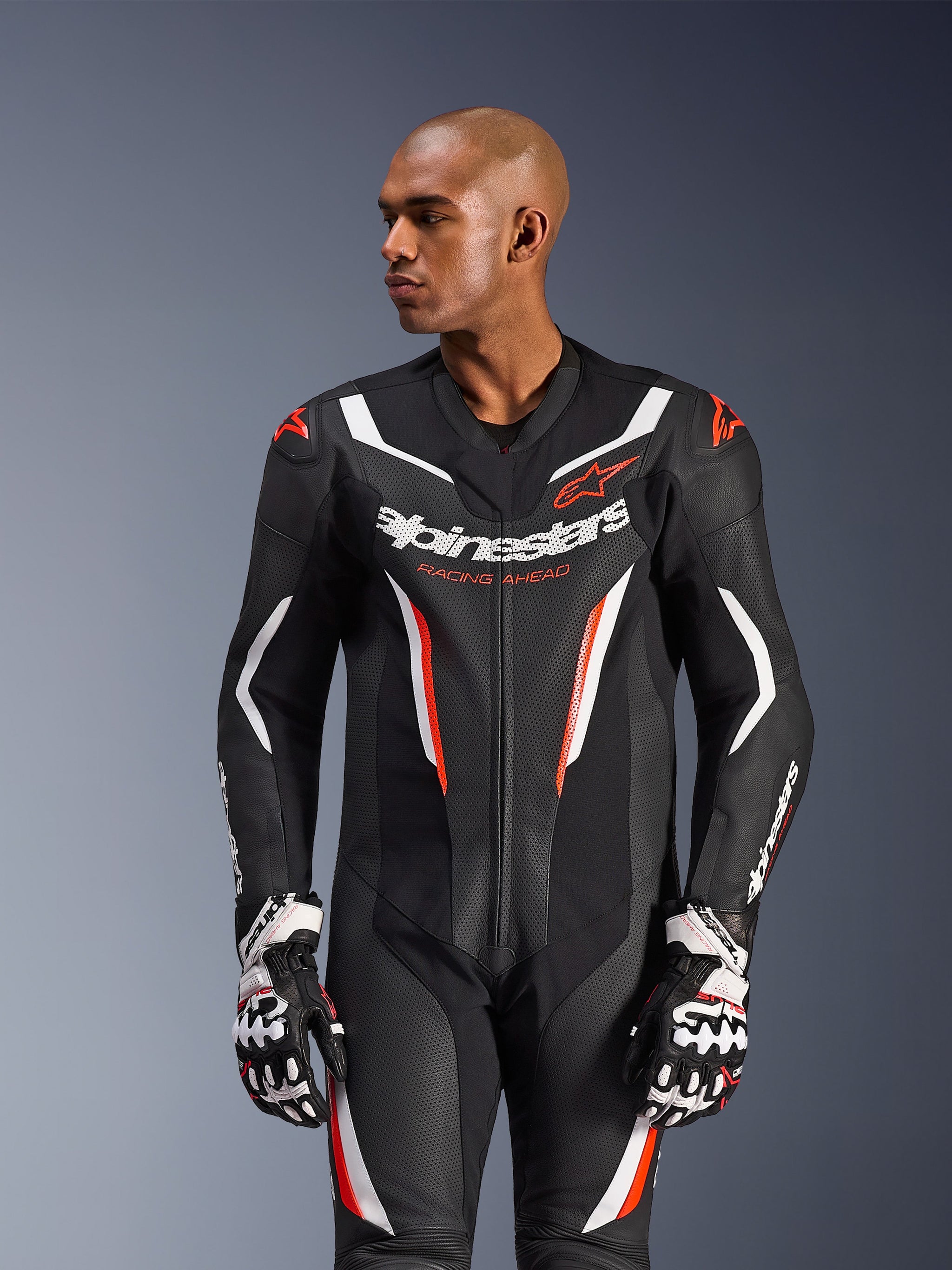 Alpinestars GP Force V2 læderdragt – 1 del, motorcykelracerdragt, sort, hvid og rød fluo, med perforerede læderpaneler, markant branding på brystet med 'Racing Ahead'-tekst og ergonomisk beskyttende design, båret med matchende racerhandsker