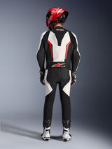 Alpinestars GP Force V2 læderdragt - 1-piece, hvid, sort og rød fluo, set bagfra med fokus på den aerodynamiske speed hump og Tech-Air Ready-branding, båret med rød racerhjelm og hvide og sorte støvler, banefokuseret læderdragt til performance-kørsel