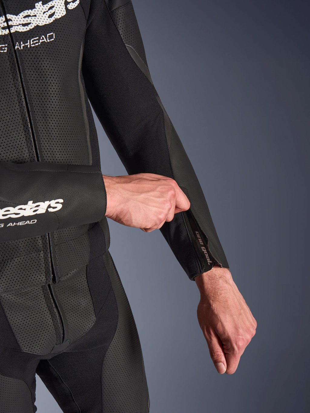 Alpinestars GP Force V2 2-delt læderdragt i sort, detaljebillede af lynlåsåbning på underarm der justeres, med perforerede læderpaneler og konstruktion i strækstof.
