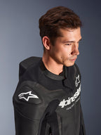 Alpinestars GP Force V2 læderdragt, 2-delt, sort, båret af en model, med hvidt Astar-logo på skulderen, brystbranding, perforerede læderpaneler og aerodynamisk speed hump, højtydende motorcykel-racerudstyr
