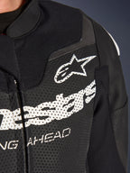 Alpinestars GP Force V2 todelt læderdragt, racing/sport motorcykeldragt, sort, nærbillede af perforeret læder på brystet med hvidt Alpinestars-logo og branding, der fremhæver ventilationshuller og tekstureret konstruktion.