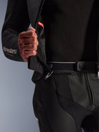 Alpinestars GP Force V2 2-Piece Læderdragt, sort, nærbillede der viser den 360-graders lynlås i taljen, der samler jakken og bukserne, med perforerede okselæderpaneler og hvid Alpinestars-branding på ærmet.
