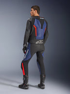 GP Force V2 Leather Suit 2-Piece, Black Blue and Red Fluo, rear profile view on a model, featuring aerodynamic hump, perforated leather, and Tech-Air Ready branding, worn with black Alpinestars racing boots and gloves