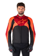 Alpinestars T-Jaws V4 Waterproof Jacket, sportstekstil motorcykeljakke, sort med rød fluo og mørkerøde detaljer, bæres af en mandlig model med matchende handsker, teknisk køreudstyr med fremtrædende stjernelogo på brystet.