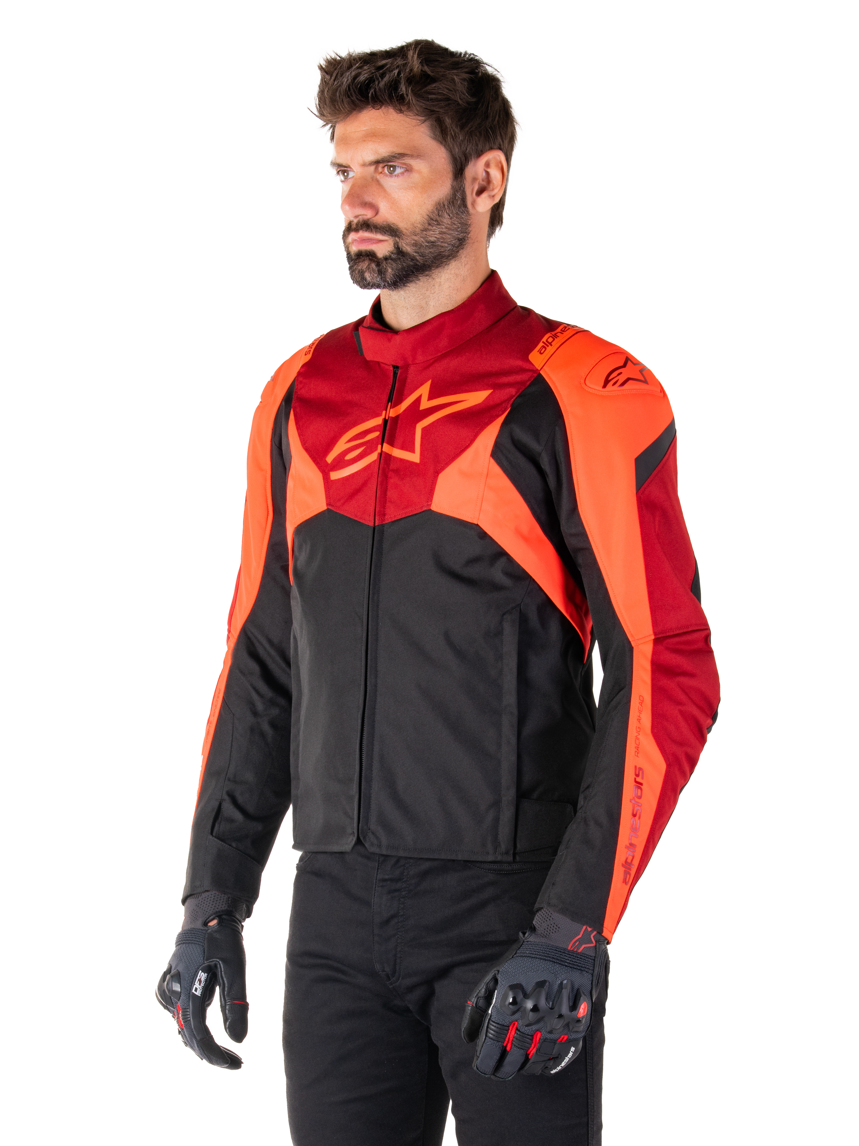 Alpinestars T-Jaws V4 vandtæt jakke, sort, fluorescerende rød og mørkerød, båret af en mandlig model med sorte bukser og motorcykelhandsker, aggressiv sportssilhuet med Alpinestars-logo på brystet, trekvart visning