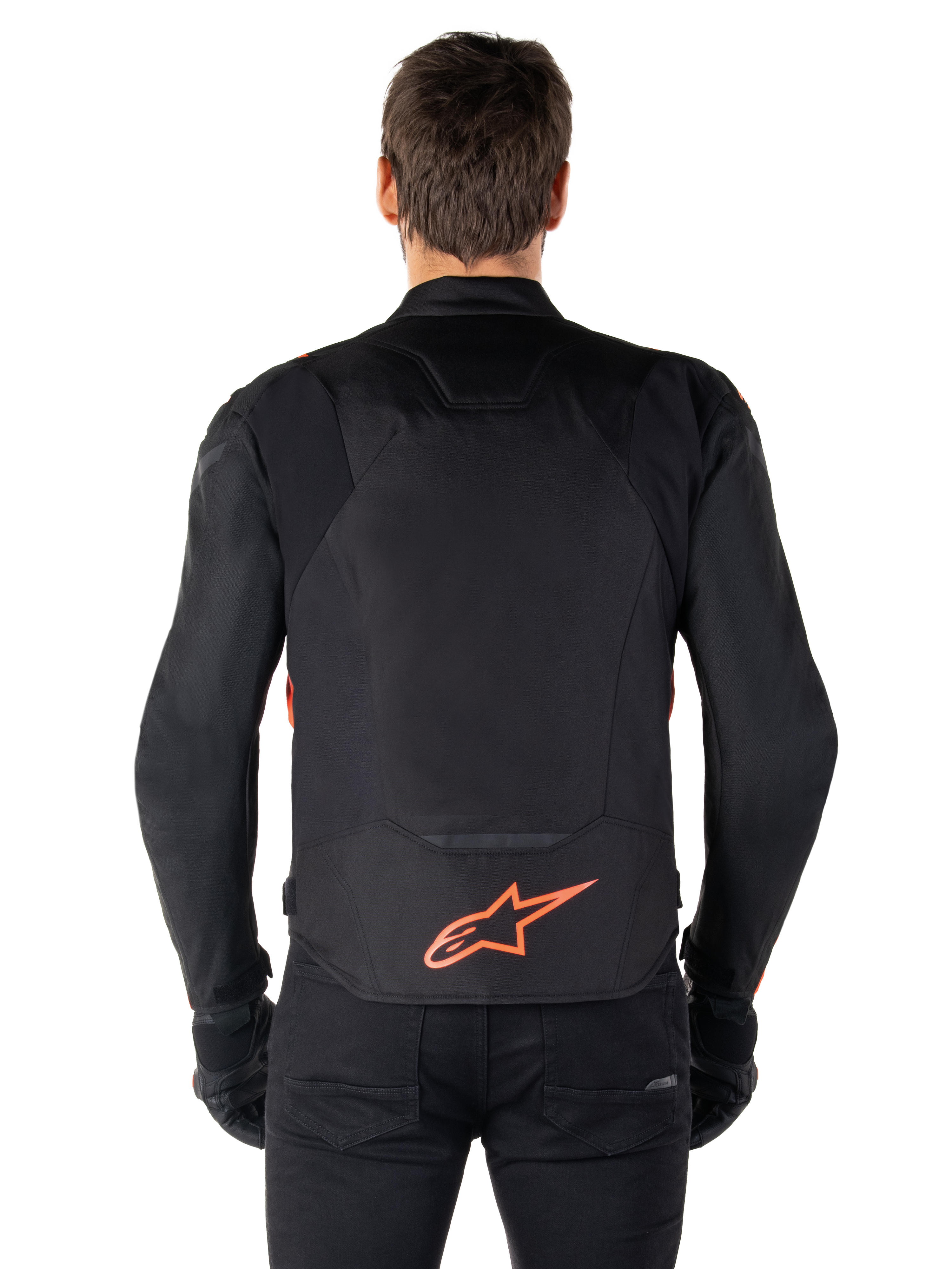 Alpinestars T-Jaws V4 vandtæt jakke, set bagfra, sort med rød fluo, med rødt Alpinestars-logo på lænden, teknisk tekstilkonstruktion, båret med sorte bukser og handsker for et komplet sportsligt kørelook