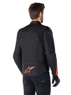 Mandlig model iført Alpinestars T-Jaws V4 Waterproof-jakke set bagfra, sort med røde fluo-detaljer, med et rødt fluo-logo nederst på ryggen og detaljer på skuldre og ærmer, sportsmotorcykeludstyr