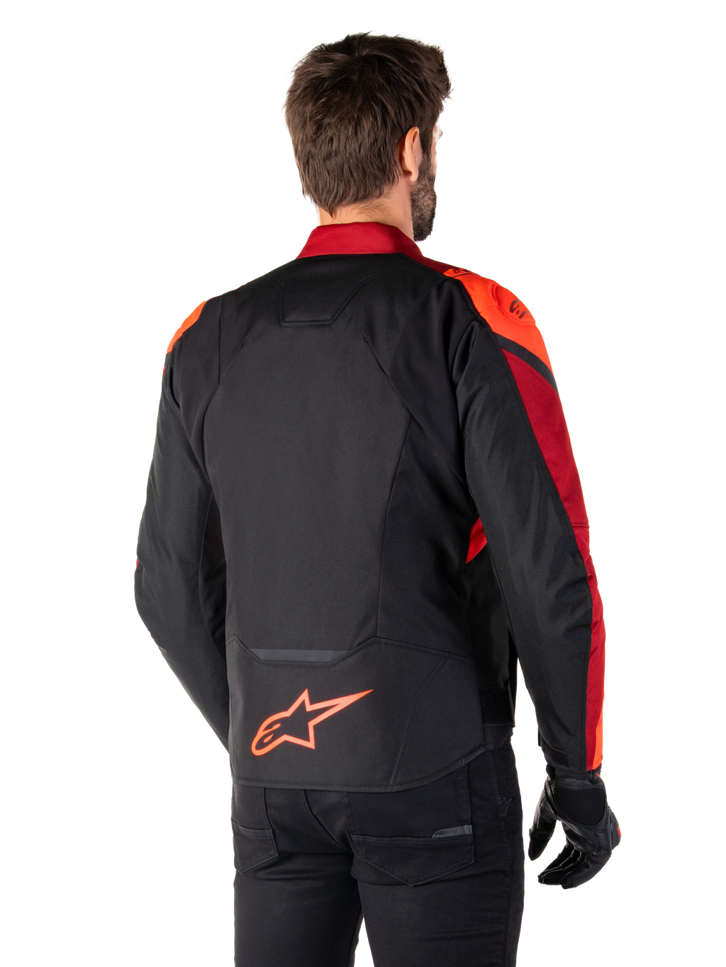 Set bagfra ses en mand iført Alpinestars T-Jaws V4 Waterproof-jakke i Black Red Fluo Dark Red, med markante røde detaljer på skuldre og ærmer, et fluorødt Alpinestars-logo på lænden, kombineret med sorte bukser og handsker.