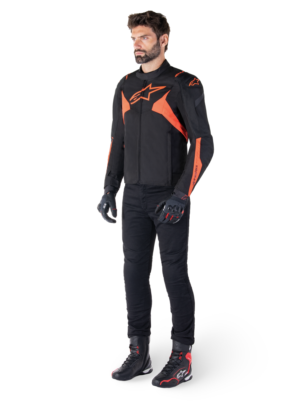 Alpinestars T-Jaws V4 vandtæt jakke, sort og rød fluo, båret af en mandlig model med sorte bukser, handsker og støvler, med klare orange detaljer og Alpinestars-logoet, sporty design til motorcykelkørsel