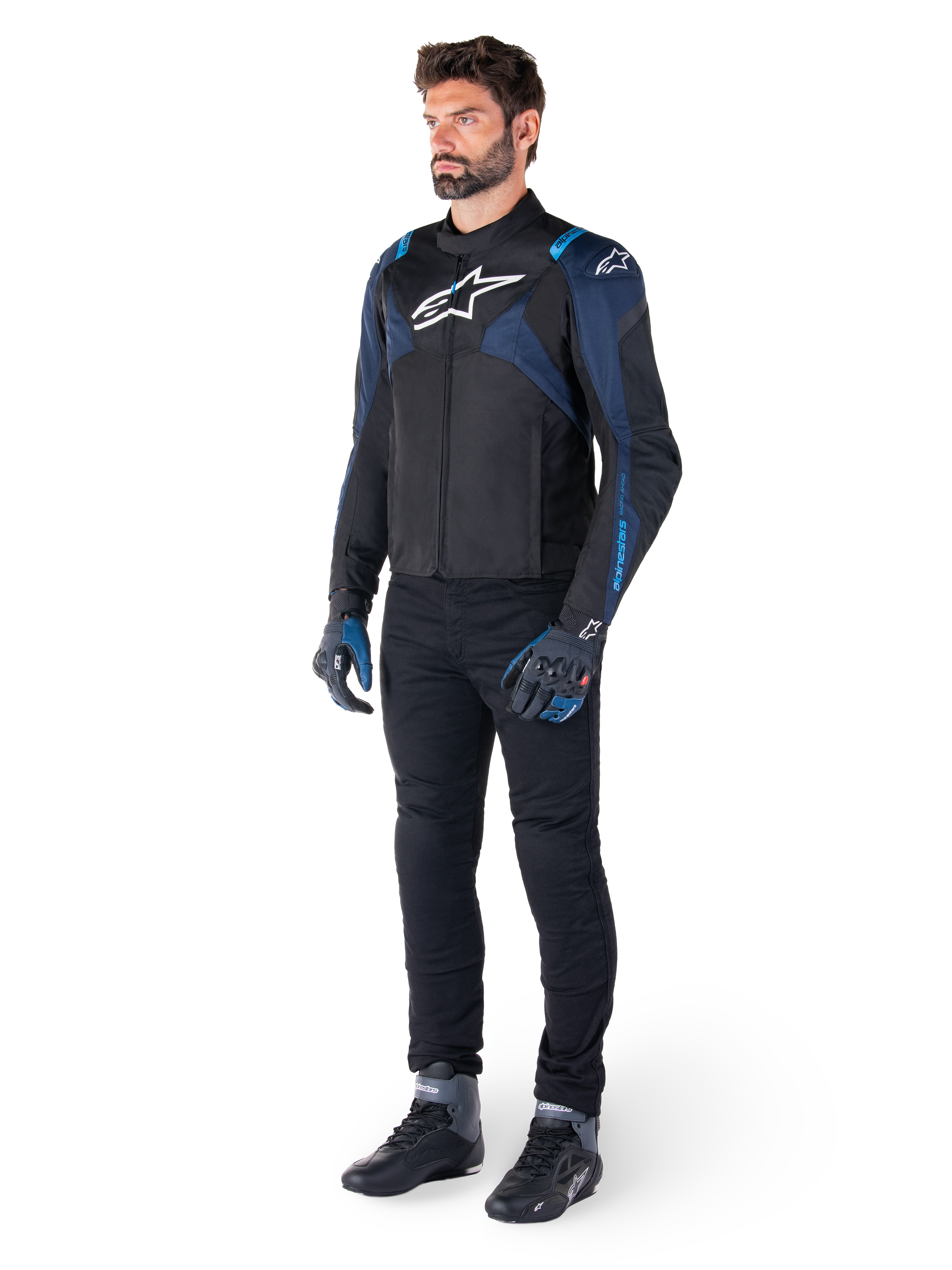 Alpinestars T-Jaws V4 vandtæt jakke, sort, mørkeblå og Blithe Blue, båret af en model med sorte motorcykelbukser og kørestøvler, hvidt Alpinestars-logo på brystet og blå skulderdetaljer, sport-fit køreudstyr