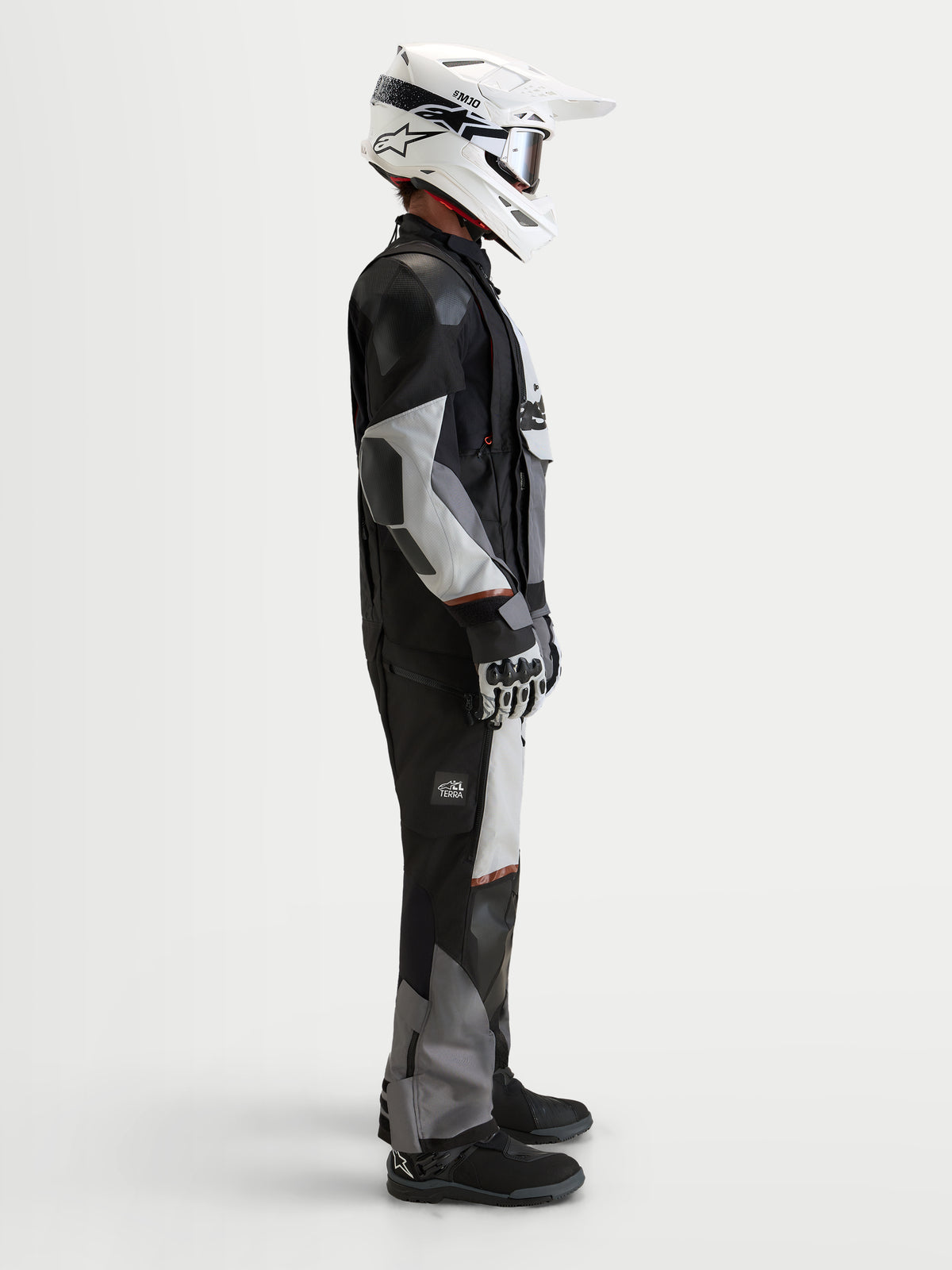 Alpinestars Harok V2 Drystar jakke, herre-motorcykeljakke til eventyr og terrænkørsel, mørkegrå, isgrå og sort, båret med hvid hjelm og køresæt i studie