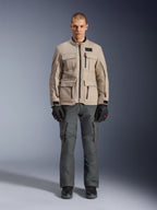 Alpinestars Borrego Drystar® jakke, adventure-motorcykeljakke, varm grå, båret af en model med mørkegrå motorcykelbukser og sorte handsker, udstyret med flere cargo-lommer og en holdbar tekstilkonstruktion med et klassisk voksbehandlet lærredslook