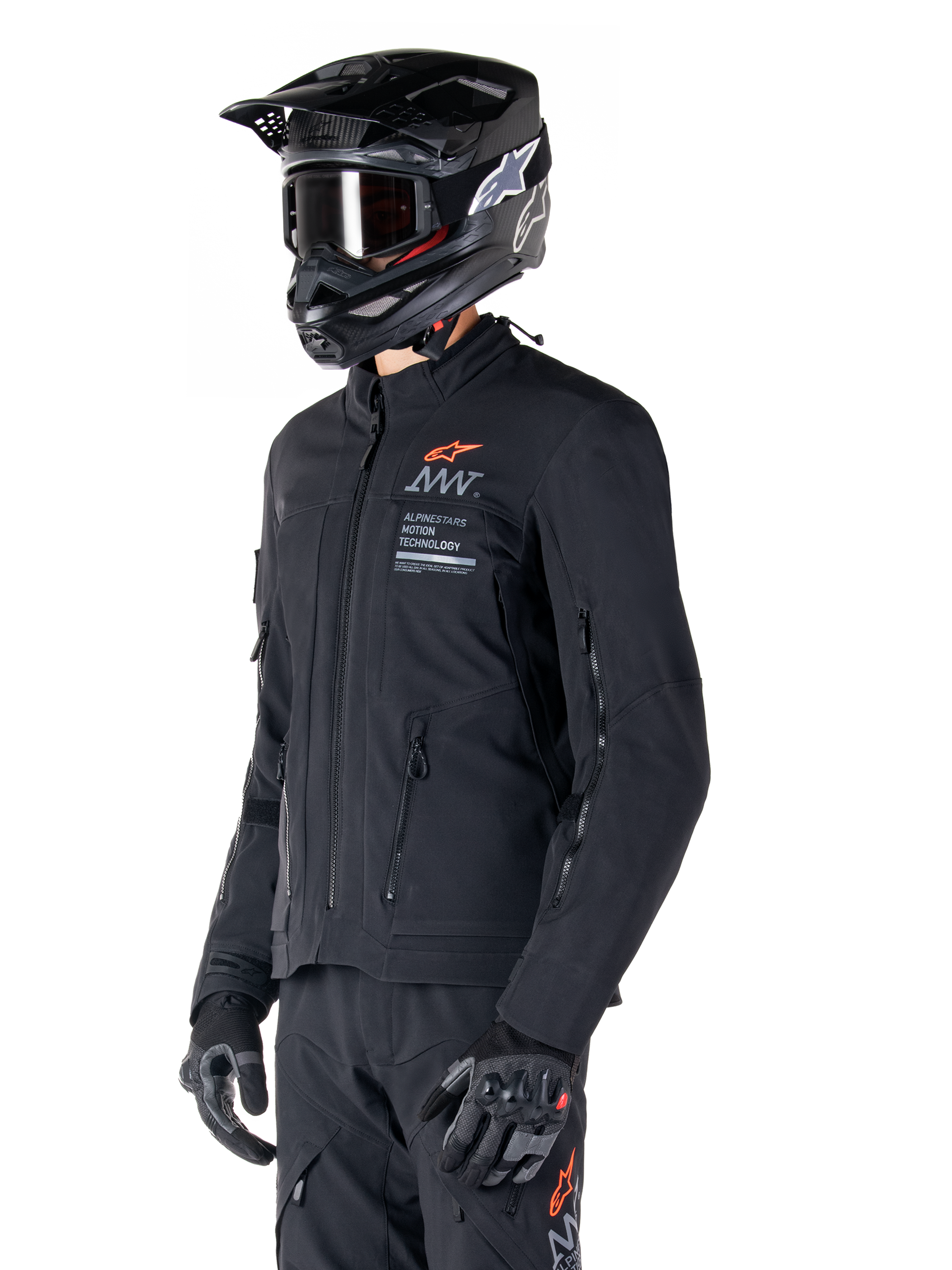Alpinestars AMT-8 Stretch Drystar® XF jakke, sort, båret af en kører med matchende adventure-bukser og -handsker, sort motocross-hjelm og goggles, ventilationsåbninger med lynlås på bryst og arme, Alpinestars Motion Technology-branding med orange logo, førsteklasses adventure-touring-udstyr
