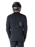 Alpinestars AMT-8 Stretch Drystar® XF jakke, set bagfra, sort, båret med sort hjelm og bukser, med Alpinestars Motion Technology-branding på ryggen, adventure touring-design med ergonomisk strækmateriale.