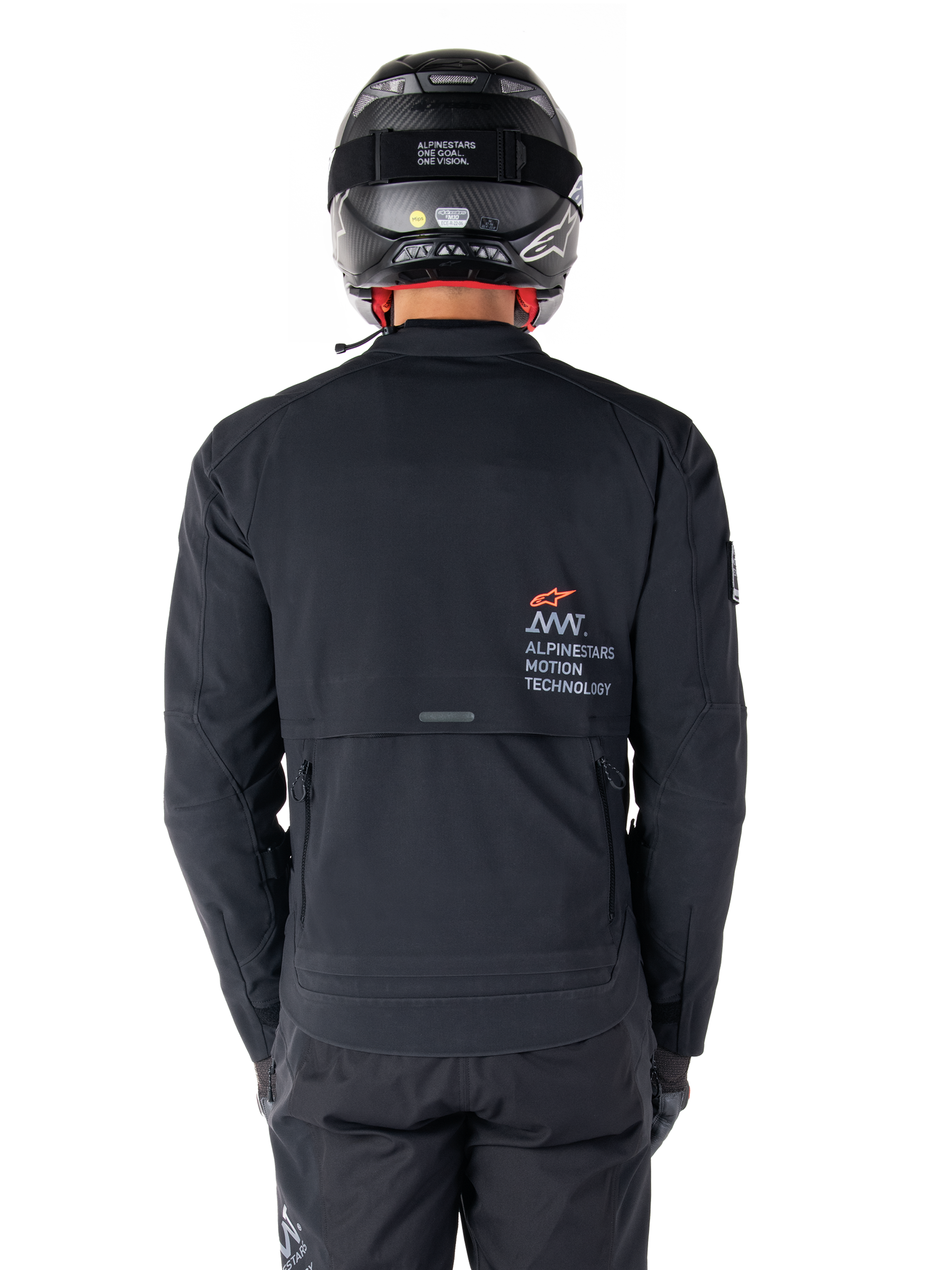 Alpinestars AMT-8 Stretch Drystar® XF jakke, set bagfra, sort, båret med sort hjelm og bukser, med Alpinestars Motion Technology-branding på ryggen, adventure touring-design med ergonomisk strækmateriale.