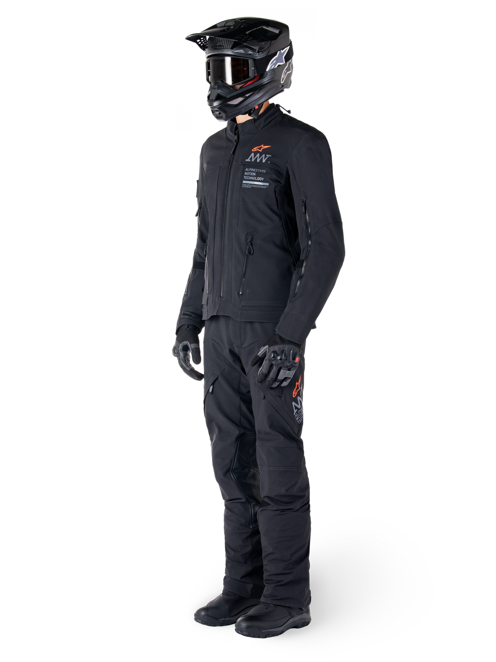 Alpinestars AMT-8 Stretch Drystar® XF-jakke, adventure-motorcykeljakke, sort, vist med matchende bukser, hjelm og handsker, med Alpinestars Motion Technology-branding og orange detaljer, slidstærk strækkonstruktion til adventure-kørsel